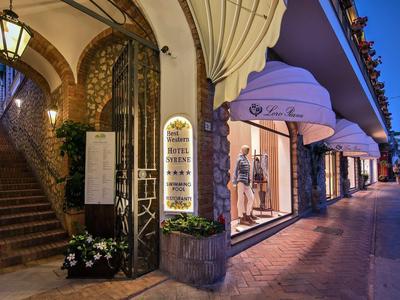 Elegante hotelentree met verlicht menu en verlicht etalageraam bij schemering.