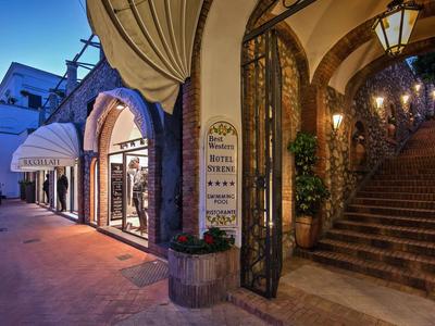 Verlichte hotelentree met trap en elegante boog in de avond