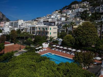 Zwembad met ligstoelen bij een hotel op een helling met witgekalkte gebouwen.