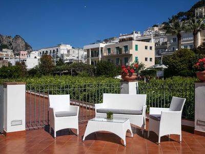 Zitgroep op terras met bergzicht en witte gebouwen bij heldere lucht.
