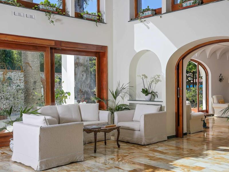 Lichte hotellounge met witte banken, glazen deuren en marmeren vloer.