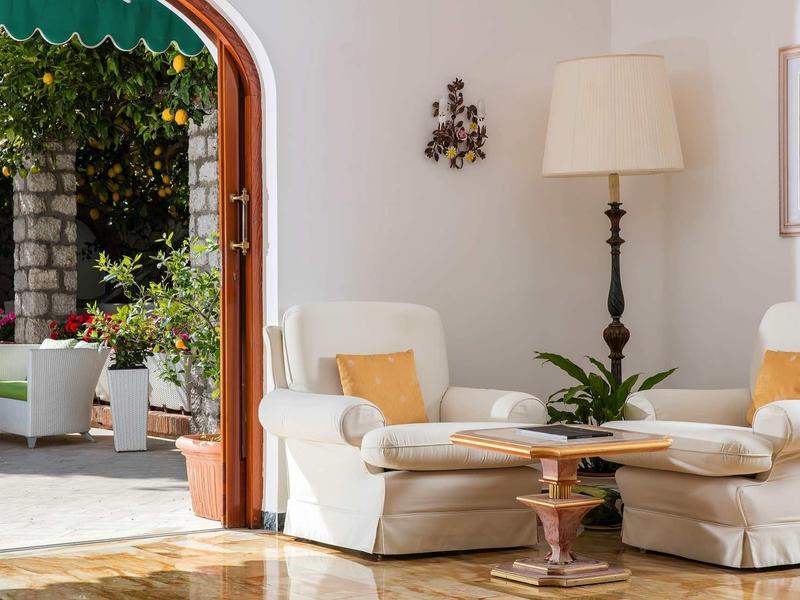 Lichte woonkamer met comfortabele fauteuils, vloerlamp en uitzicht op een zonnig terras.