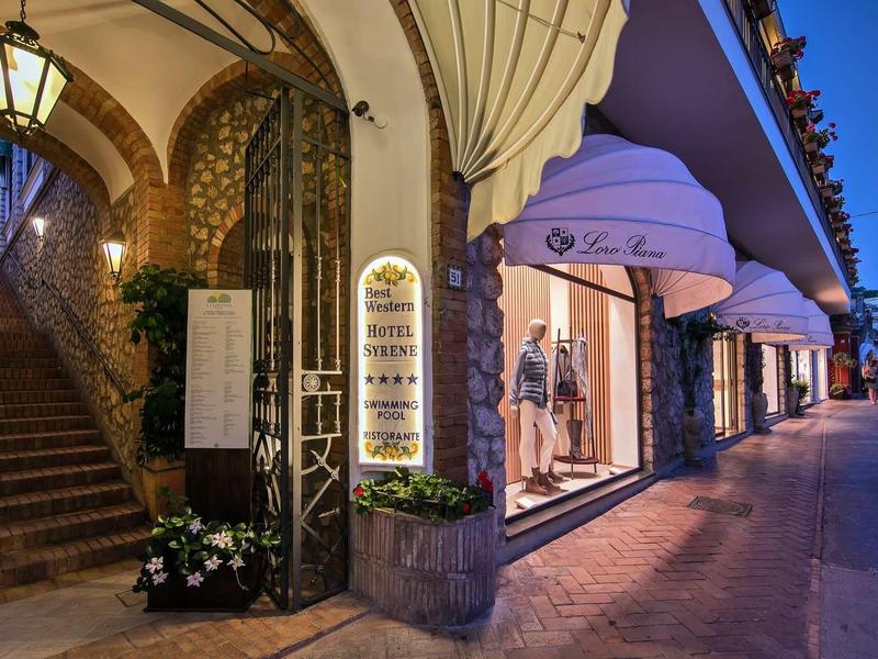 Elegante hotelentree met verlicht menu en verlicht etalageraam bij schemering.