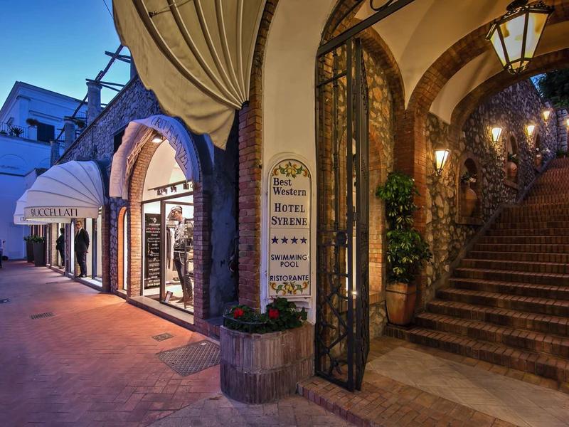 Verlichte hotelentree met trap en elegante boog in de avond