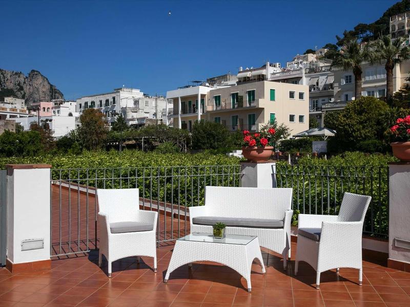 Zitgroep op terras met bergzicht en witte gebouwen bij heldere lucht.