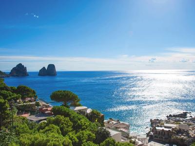 Kustlandschap met blauwe zee, rotsen in het water en groene bomen onder een heldere lucht