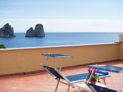 Terrasse mit Liegestühlen und Blumendekoration mit Blick auf das Meer und Felsen
