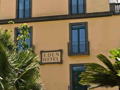 Gelbes Hotelgebäude mit Balkonen und grünen Pflanzen im Vordergrund