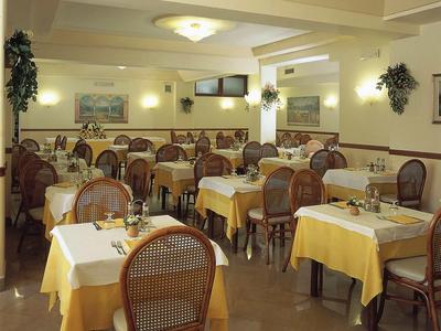 Hell beleuchteter Speisesaal mit braunen Holzstühlen und gelben Tischdecken in einem Restaurant.