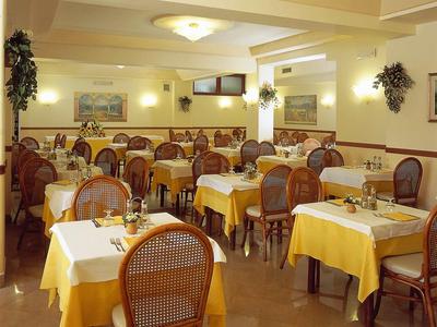 Gemütlicher Speisesaal mit Holzmöbeln, gelben Tischdecken und gedeckten Tischen.