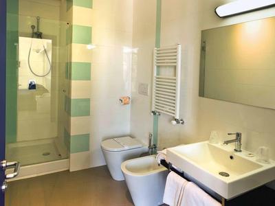 Helles, modernes Badezimmer mit Duschkabine, Toilette, Bidet, großem Spiegel und Waschbecken.