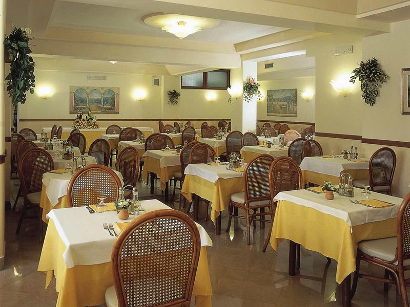 Hell beleuchteter Speisesaal mit braunen Holzstühlen und gelben Tischdecken in einem Restaurant.