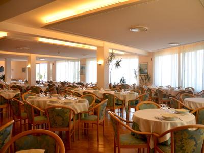 Eleganter Frühstücksraum mit runden Tischen, Stühlen und großen Fenstern in einem Hotel.