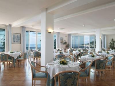 Helles Hotelrestaurant mit gedeckten Tischen und großem Meerblickfenstern