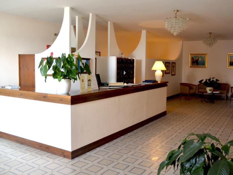 Recepcja hotelowa z roślinami i miejscem do siedzenia w tle.