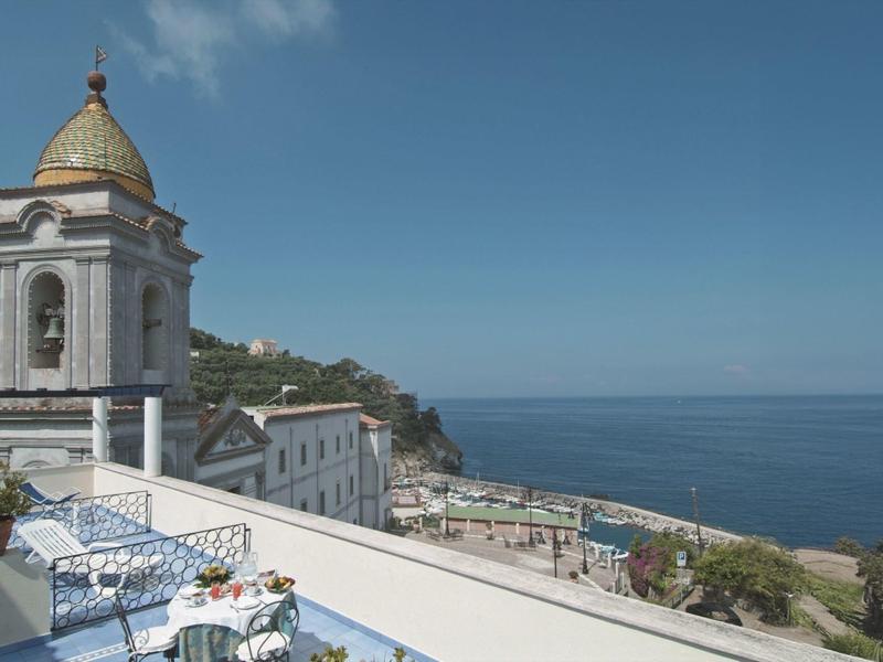 Taras z krzesłami i stołami z widokiem na kościół i morze pod czystym niebem.