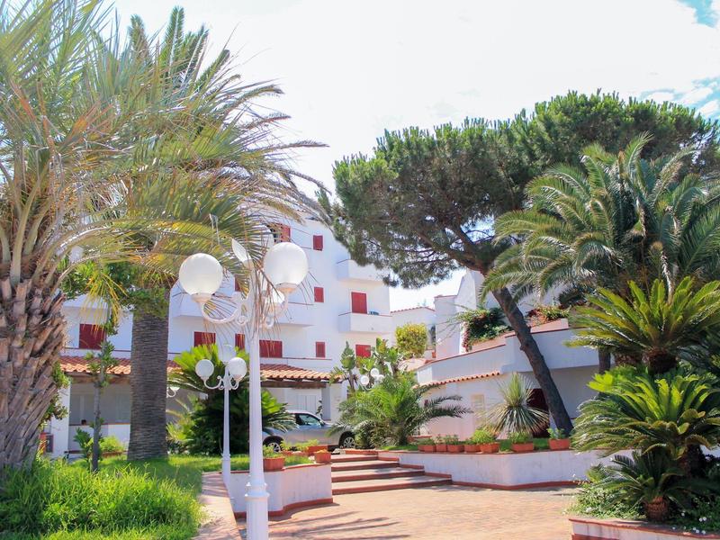 Hotel complex with palm trees and white buildings under blue sky