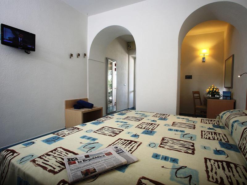 Cozy hotel room with double bed, wall-mounted TV, and walk-in closet area.