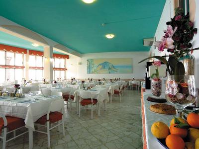 Heller Speisesaal mit weiß gedeckten Tischen und Frucht- sowie Blumenarrangement im Vordergrund.