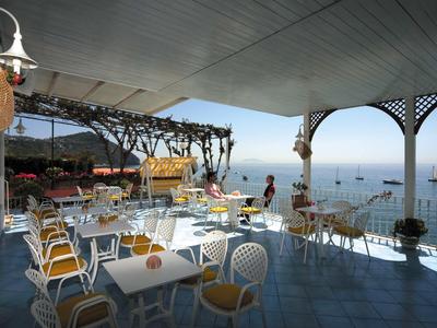 Offener, überdachter Essbereich mit Blick aufs Meer, Stühle und Tische sind angeordnet.