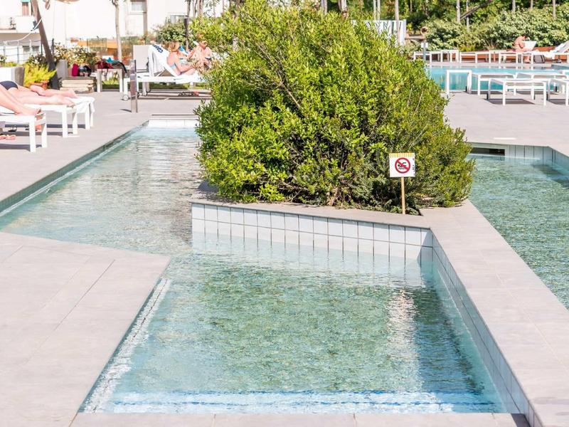 Acqua limpida che scorre in una fontana moderna dell'hotel con una grande siepe al centro.