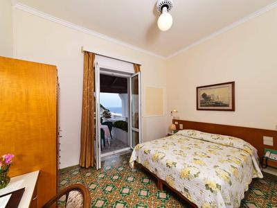 Pohodlný hotelový pokoj s manželskou postelí, přístupem na balkon a barevnou podlahou.