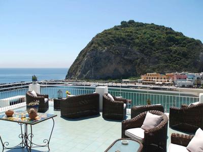 Terrasse avec sièges confortables et vue sur la mer et une colline verdoyante