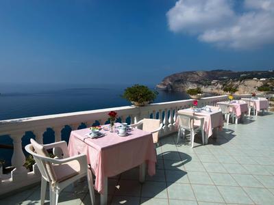 Terasa s prostřenými stoly s výhledem na moře pod jasnou oblohou.