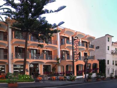 Großes, mehrstöckiges Gebäude mit Arkaden, Balkonen und roten Ziegeldächern bei klarem Himmel.