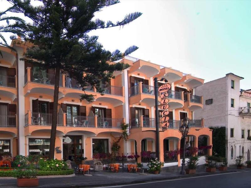 Modern hotel with multiple floors, balconies, and palm trees in front