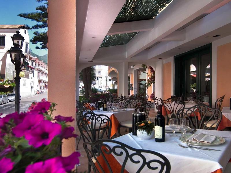 Restaurant terrace with set tables and a bottle of wine in a warm, inviting setting.