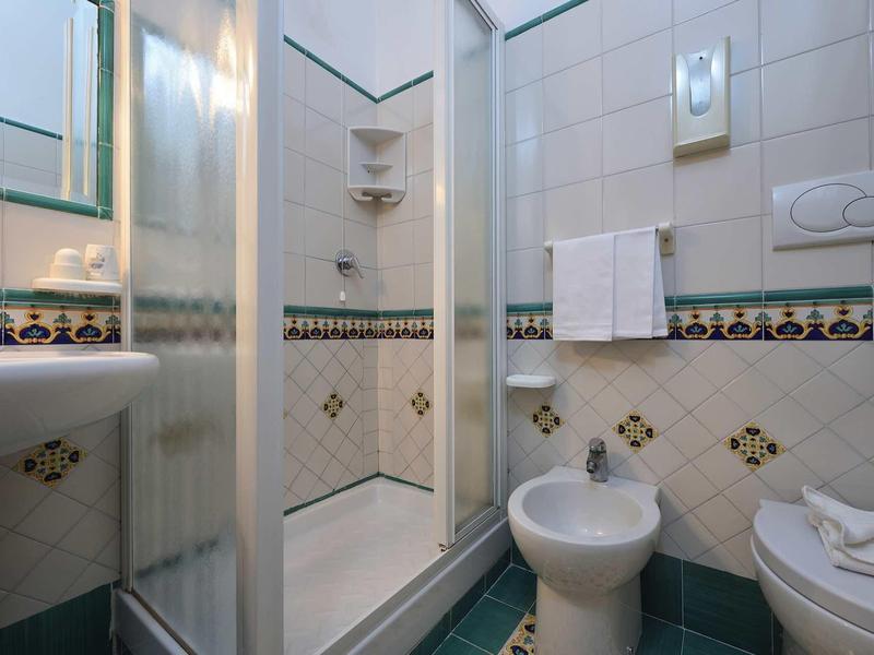 Small bathroom with shower, sink, bidet, and towels.