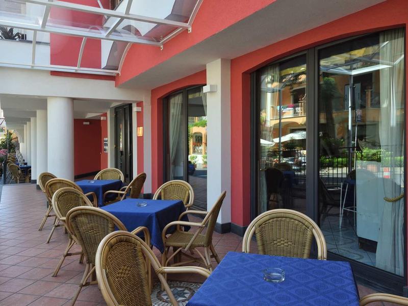 Outdoor terrace with tables, chairs, and blue tablecloths at a hotel or café.
