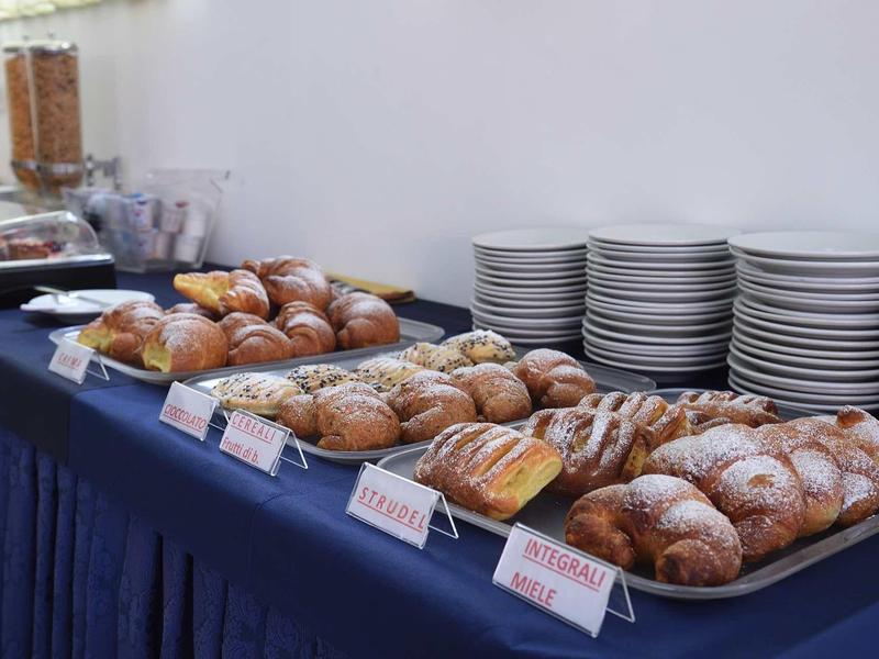 Buffet with various bread types and stacked white plates, ideal for breakfast.