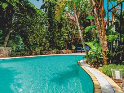 Piscina redonda de hotel rodeada de vegetación exuberante y plantas tropicales.