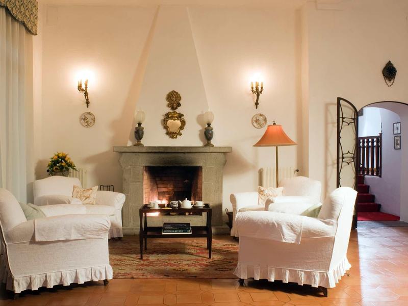 Bright living room with fireplace, white armchairs, and classic decor.