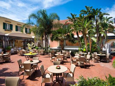 Einladender Außenbereich mit Terrassenmöbeln, Palmen und klarem Himmel in mediterranem Stil.