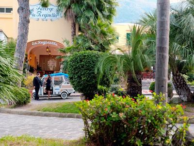 Façade de l'hôtel avec plantes tropicales et voiturette de golf près de l'entrée.