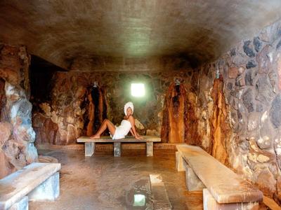 Personne assise sur un banc en bois dans une pièce rocheuse semblable à une grotte avec une petite fenêtre.