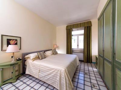 Chambre lumineuse avec lit double, armoire verte et sol à carreaux.
