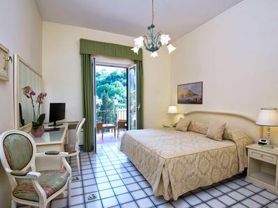 Chambre d'hôtel confortable avec lit double, bureau, chaise et accès au balcon