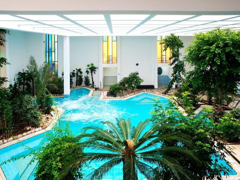 Piscine intérieure dans un hôtel moderne avec des plantes et de grandes fenêtres