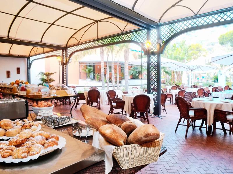 Coin restaurant extérieur confortable avec tables dressées et pâtisseries fraîches.