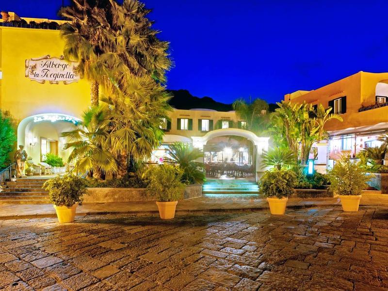 Bâtiment d'hôtel éclairé avec palmiers et fontaine la nuit