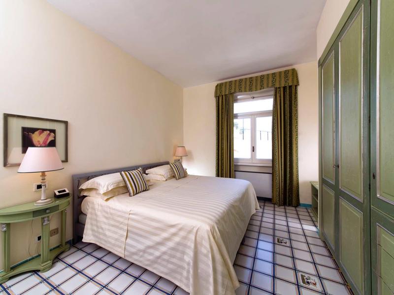 Chambre lumineuse avec lit double, armoire verte et sol à carreaux.