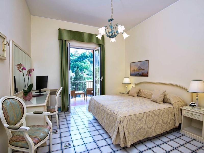 Chambre d'hôtel confortable avec lit double, bureau, chaise et accès au balcon