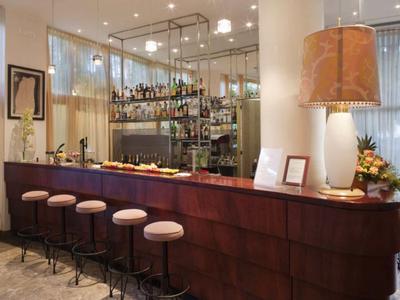 Elegante Bar mit dunklem Holz, sechs Hockern und einer großen Lampe auf der Theke.