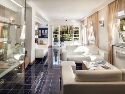 Jasna, nowoczesna strefa wypoczynkowa hotelu z białymi sofami i dużymi oknami.