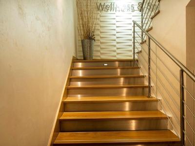 Drewniane schody z oświetleniem stopni prowadzące do dobrze oświetlonego spocznika.