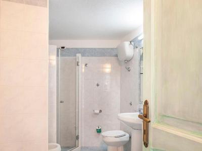 Mała łazienka z prysznicem, toaletą i umywalką w neutralnych kolorach.